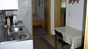 A compact kitchen with a stove, sink, and a small dining table. - Charmantes Apartment in Jennewitz, in Ostseenähe (Jennewitz)