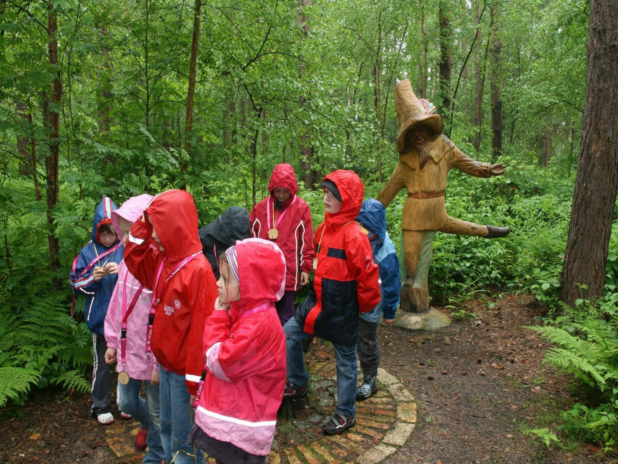 A group of people in a forested area with a large wooden statue.