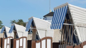 Beach huts with striped awnings, wooden doors, and a sandy beach in the background. - Charmantes Apartment in Jennewitz, in Ostseenähe (Jennewitz)