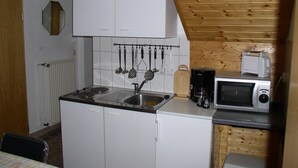 A compact kitchen with white cabinets, a built-in microwave, and a coffee maker. - Charmantes Apartment in Jennewitz, in Ostseenähe (Jennewitz)
