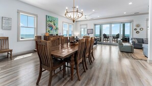 A spacious dining area with a wooden table and chairs, a chandelier, and large windows offering ocean views. - All open summer weeks just discounted up to 25%! Book now for lowest rates of th (Cape San Blas)