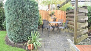 Eine Terrasse mit Holzzaun, einem runden Tisch mit Stühlen und einem Blumentopf.