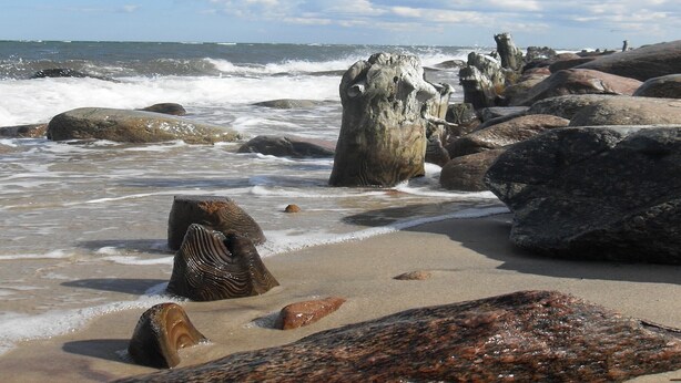 A rocky beach with large boulders and waves crashing onto the shore.
