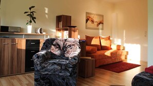 A modern living room with a sofa, a chair, a red rug, and a painting on the wall.