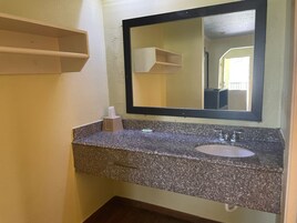 Un baño con encimera de granito, lavamanos, espejo y dispensador de pañuelos.
