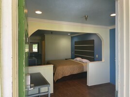 Un dormitorio con cama, escritorio y ventana.