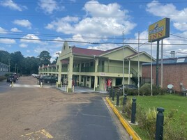 Un motel de estructura de dos pisos, un letrero de Coca-Cola y un estacionamiento con coches.