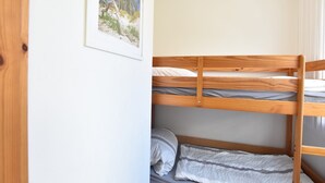A bunk bed with two levels, a framed picture on the wall, and a window with curtains. - Ferienwohnung auf dem Land in Strandnähe (Kröpelin / OT Diedrichshagen)