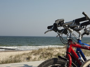 A bicycle parked on a concrete surface near a beach with the ocean in the background. - Ferienwohnung auf dem Land in Strandnähe (Kröpelin / OT Diedrichshagen)