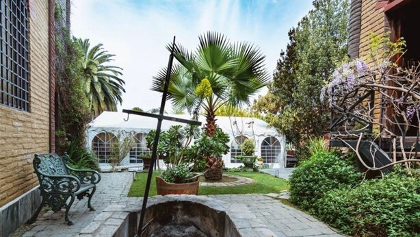 Un patio con un banco de piedra, una palmera y un muro de ladrillo.