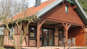 A wooden house with a sloped roof and a covered porch. - Gemütliches Appartement in Brusow mit Garten (Kröpelin)