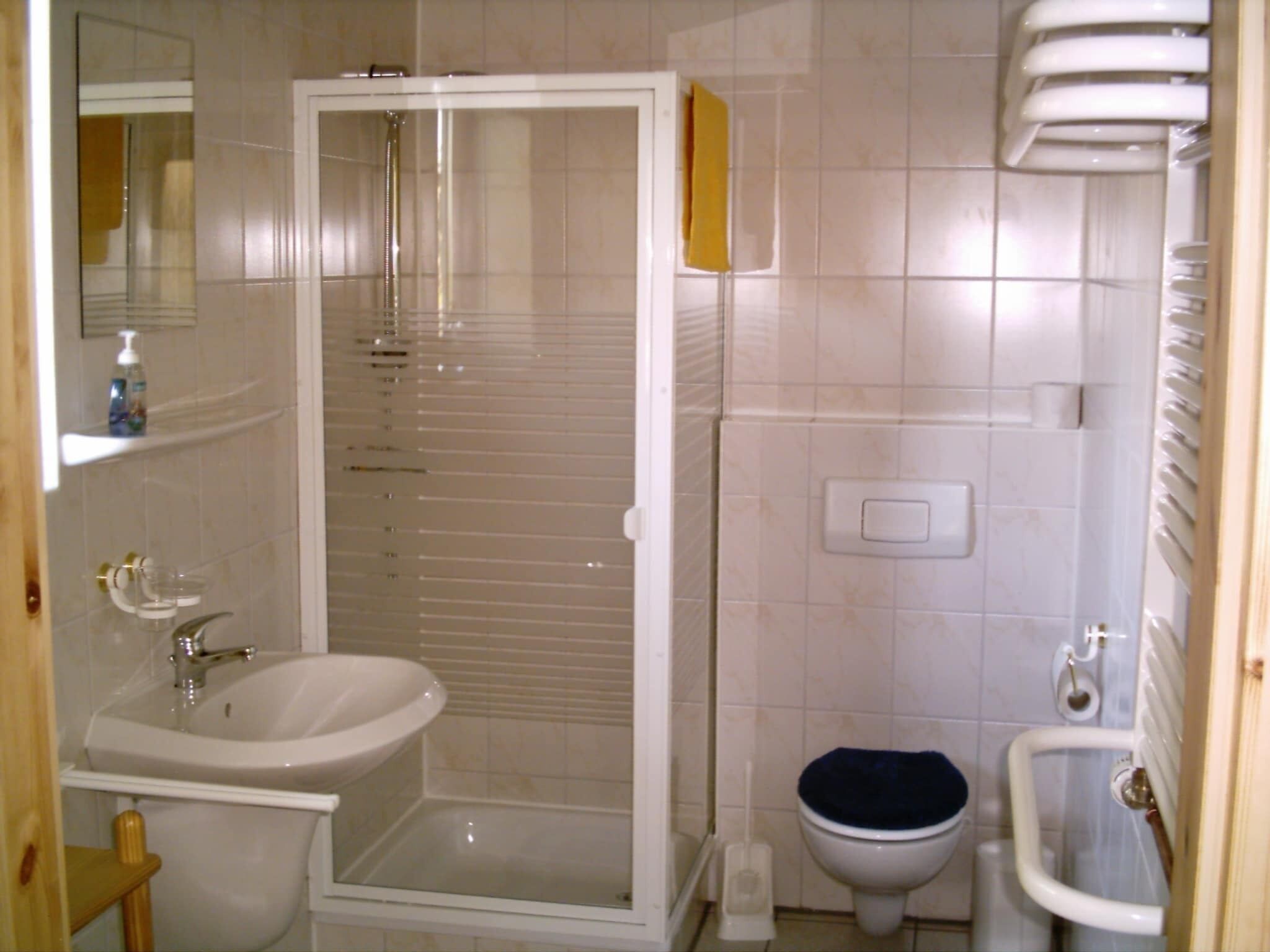 Ein Badezimmer mit Dusche, Waschbecken, Toilette und Spiegel.