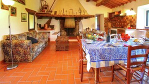 Un interno rustico con un'area pranzo, un divano e un camino.