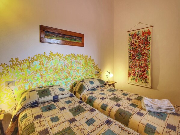 Ein Zimmer mit zwei Betten, einem Nachttisch mit Lampe, einem Wandbild und einem auf dem Bett gefalteten Handtuch.