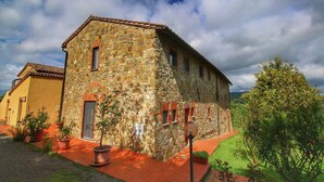 Un edificio in pietra con tetto rosso, una piccola porta e piante in vaso.