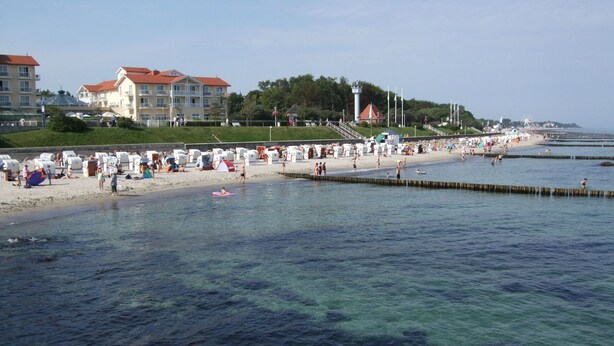 Una spiaggia con acque cristalline, una riva sabbiosa e edifici sullo sfondo.