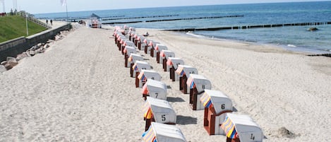 Ein Strand mit Reihen nummerierter Strandkörbe entlang der Küste.