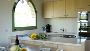 A modern kitchen with a central island, wooden cabinets, and a large window.