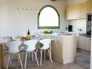 A modern kitchen with a central island, wooden cabinets, and a large window.