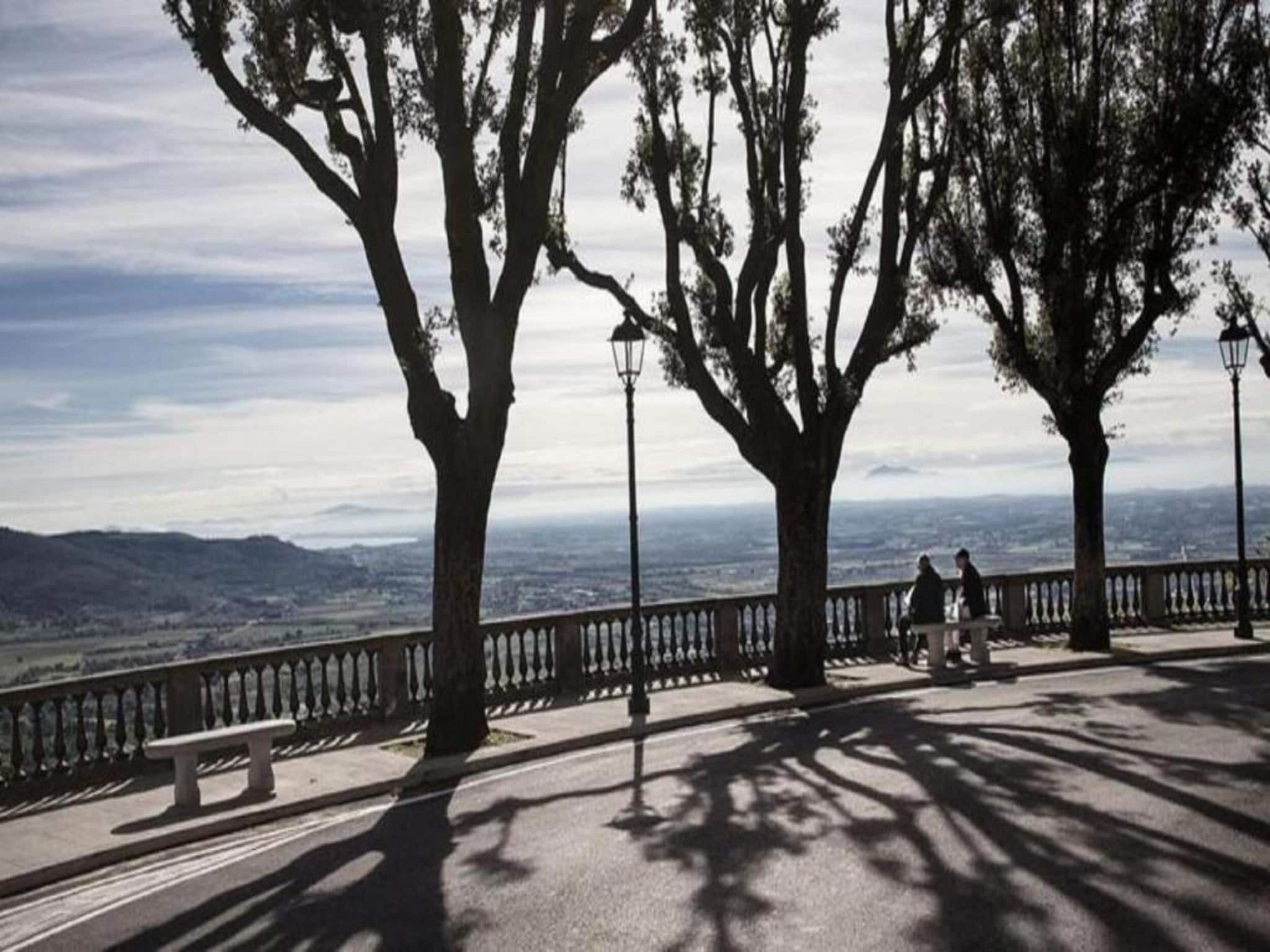 Eine Parkbank mit Blick auf eine Stadtlandschaft und Berge in der Ferne.