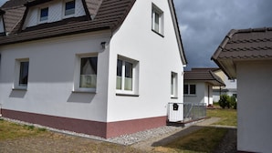 A modern two-story house with a sloped roof, white exterior walls, and a small front porch. - Exklusiver Bungalow mit Terrasse in Rerik (Rerik)