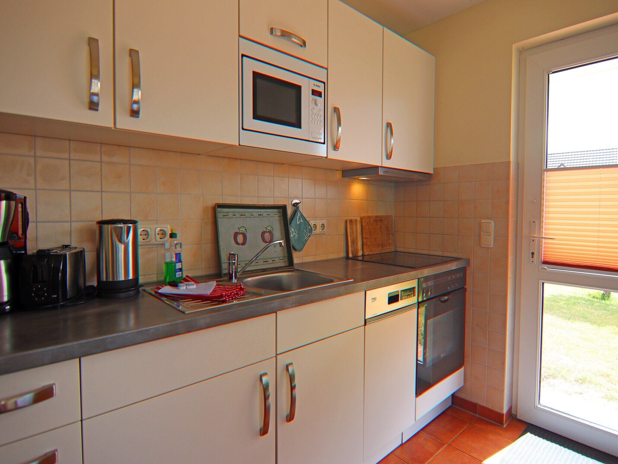 A kitchen with a dishwasher, oven, and a window with blinds.