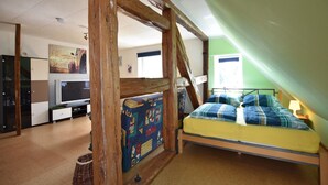 A bedroom with a loft bed, wooden beams, a television, and a green wall. - Wohnung in Groß Strömkendorf (Groß Strömkendorf)