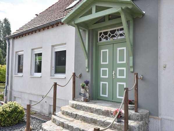 A building with a green door, white-framed windows, and stone steps leading to the entrance. - Wohnung in Groß Strömkendorf (Groß Strömkendorf)