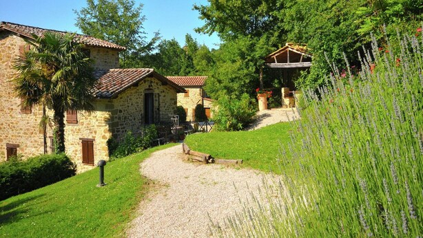 Un bâtiment en pierre avec un chemin de gravier menant à une structure en bois.