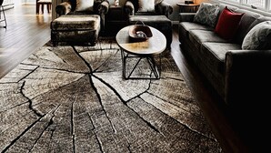 Ein geräumiges Wohnzimmer mit großem Teppich, verschiedenen Sitzmöglichkeiten und einem Essbereich im Hintergrund.