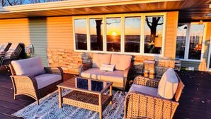 Eine Terrasse mit Korbmöbeln, einem gemusterten Teppich und einer Ziegelwand.