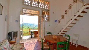 A room with a dining table and chairs, a sofa, a TV, and a staircase. - Charming Tuscan Home Wi-Fi (Castagneto Carducci)