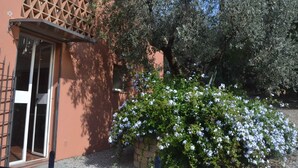 A building with a lattice window, a door, and a garden with white flowers. - Charming Tuscan Home Wi-Fi (Castagneto Carducci)