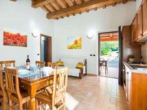 A dining area with wooden furniture, a table set for two, and a sofa. - Farmhouse in Apecchio with Pool (Apecchio)