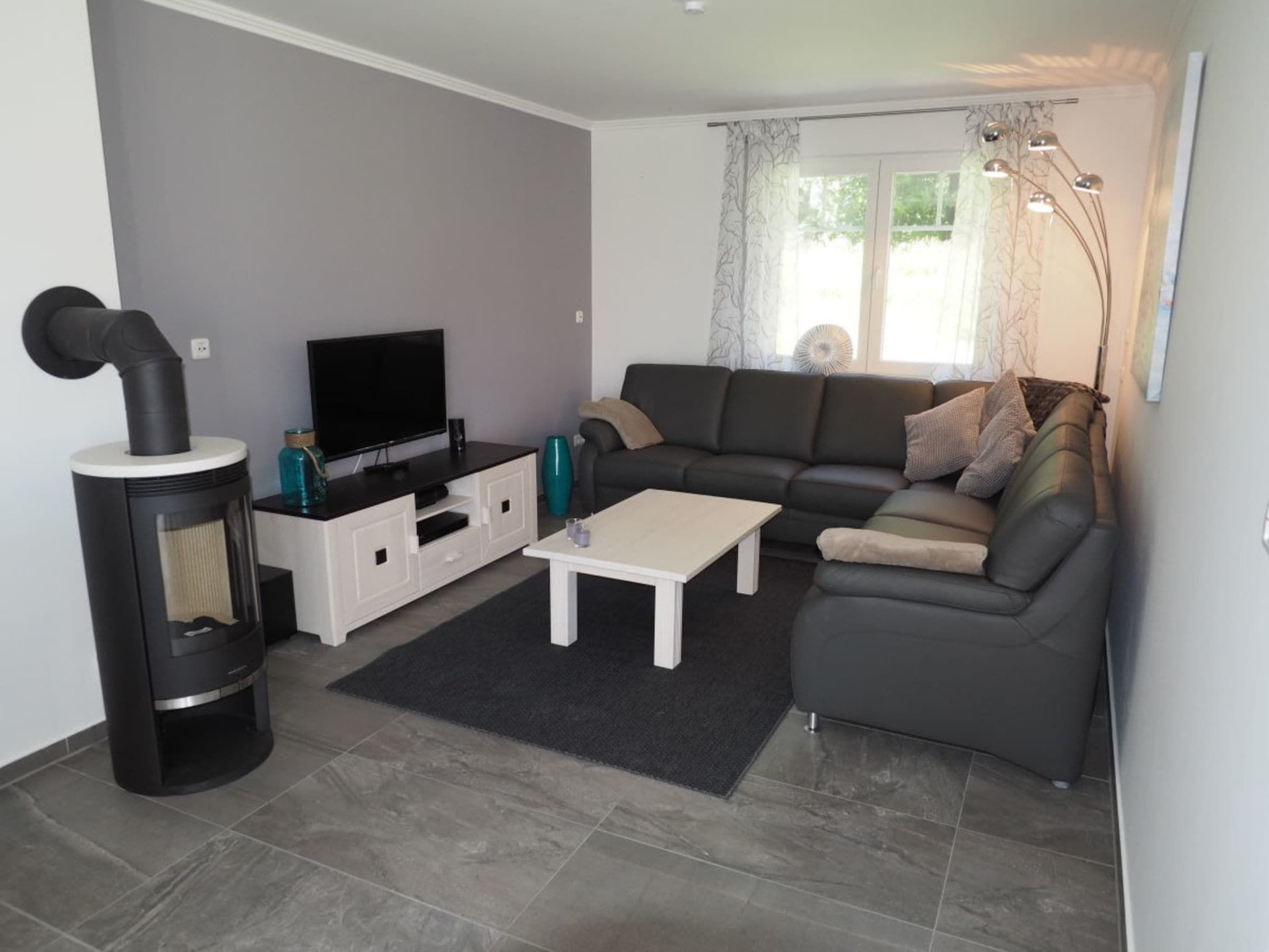 Un salon moderne avec un canapé, une table basse, un téléviseur et une cheminée.