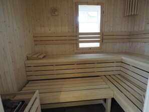 A sauna with wooden benches and a window. - Ferienhaus in Rerik mit Garten (Rerik)