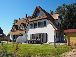 A two-story house with a thatched roof, large windows, and a well-maintained lawn. - Ferienhaus in Rerik mit Garten (Rerik)