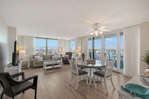 A spacious living room with a dining area, large windows, and a ceiling fan. - Anchorage 610 (Siesta Key)