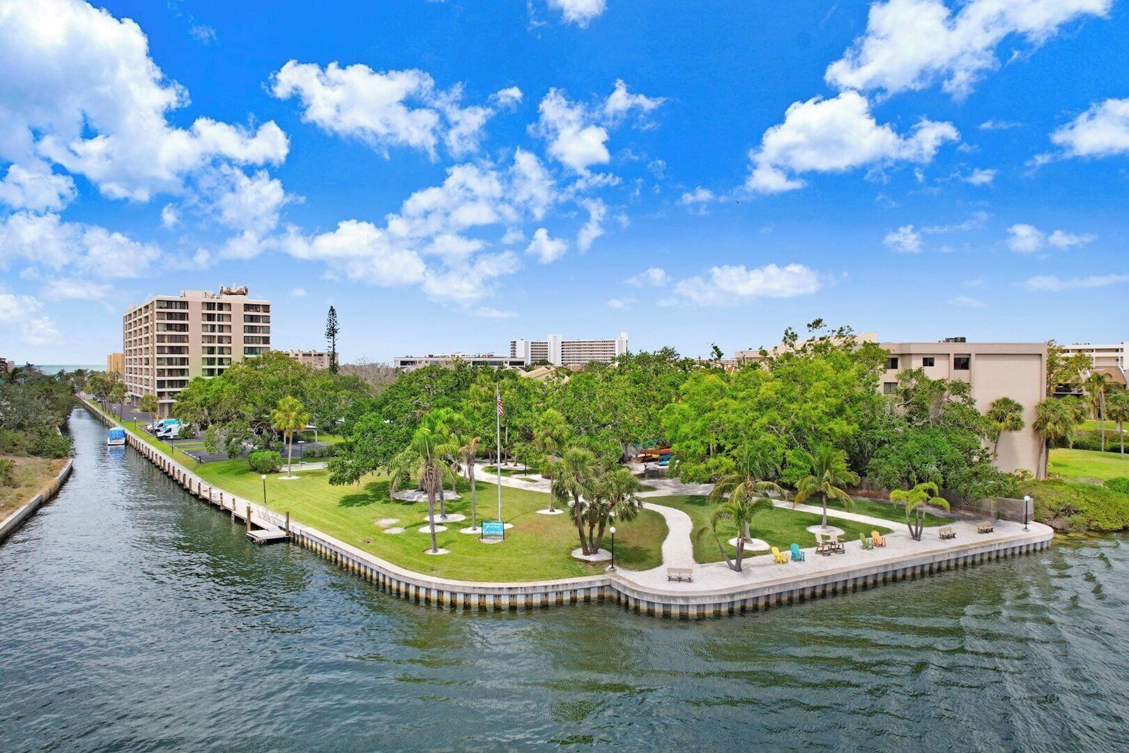 A waterfront hotel with a canal, lush greenery, and a clear blue sky.