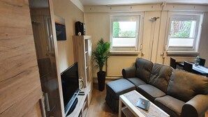 Ein kompakter Wohnbereich mit Fernseher, Sofa und einem kleinen Tisch.