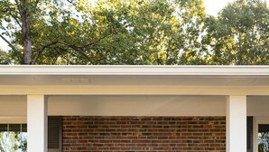 A brick house with a dark front door, white trim, and a small porch. - Spacious 6 bedroom home near Downtown Macon! (Macon)