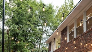 An outdoor patio with a table and chairs, surrounded by a brick building and trees. - Spacious 6 bedroom home near Downtown Macon! (Macon)