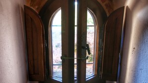 Una puerta con contraventanas de madera, una pared de piedra y vistas a un espacio exterior.