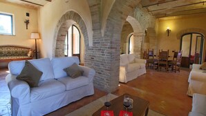 A spacious living area with a white sofa, a wooden coffee table with wine glasses, and a brick archway.