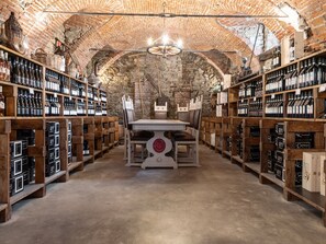 A wine cellar with wooden shelves and a central table.