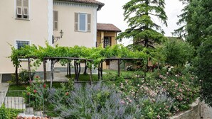 Une cour dotée d’un toit en tuiles, d’un mur en pierre et d’une pergola couverte de plantes grimpantes.