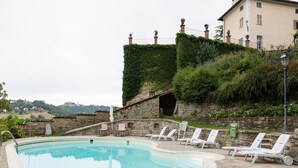 Un espace piscine avec des chaises longues et un mur en pierre.
