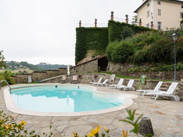 A pool area with lounge chairs and a stone wall.