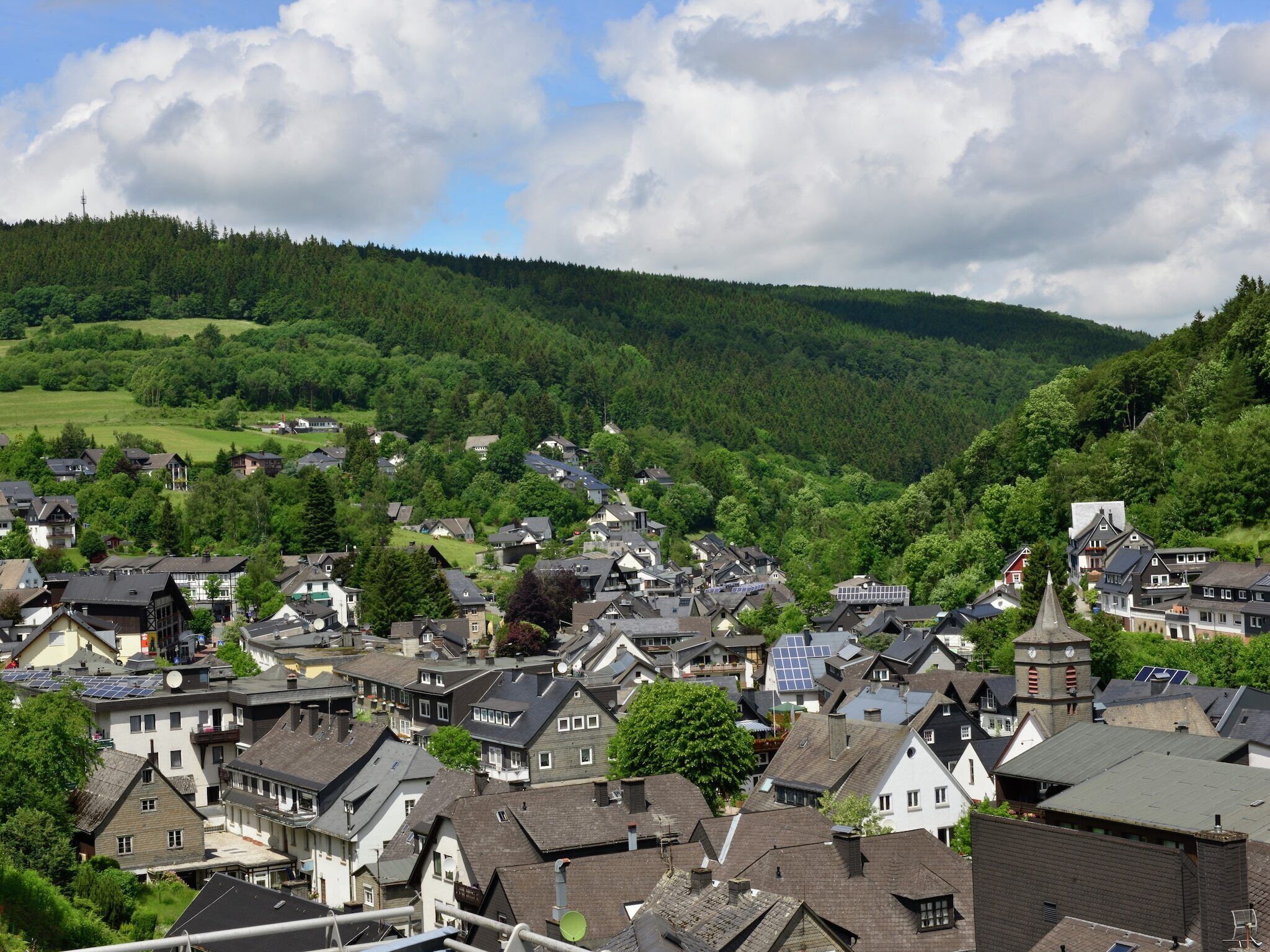 A town with traditional European architecture, including houses with steep roofs and a prominent church tower.