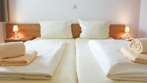 A hotel room with two beds, each with a pillow, a nightstand with a lamp, and a rolled towel on the bed. - Modernes Apartment in Willingen mit Balkon (Willingen)